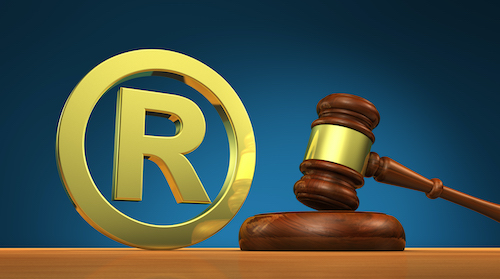 Registered trademark law business concept with golden trade mark symbol and a wooden gavel 3D illustration.